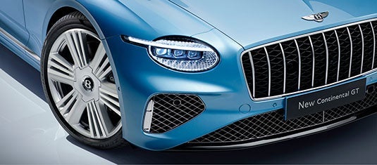 Close-up of the Bentley Continental GT Azure’s front fascia, featuring signature crystal-cut LED headlights, a prominent vertical grille, and diamond-mesh air intakes.