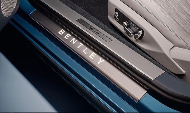 Bentley-branded illuminated door sill plate with Azure trim detail and metallic controls on the seat.