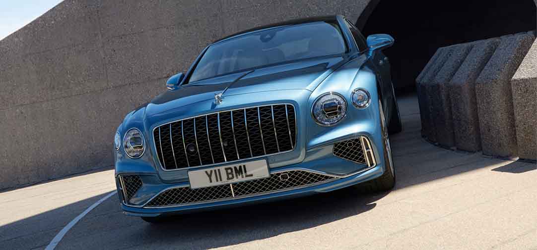 Front view of the Bentley Flying Spur Azure emerging from a curved tunnel, emphasizing its assertive grille, muscular body, and confident road presence.