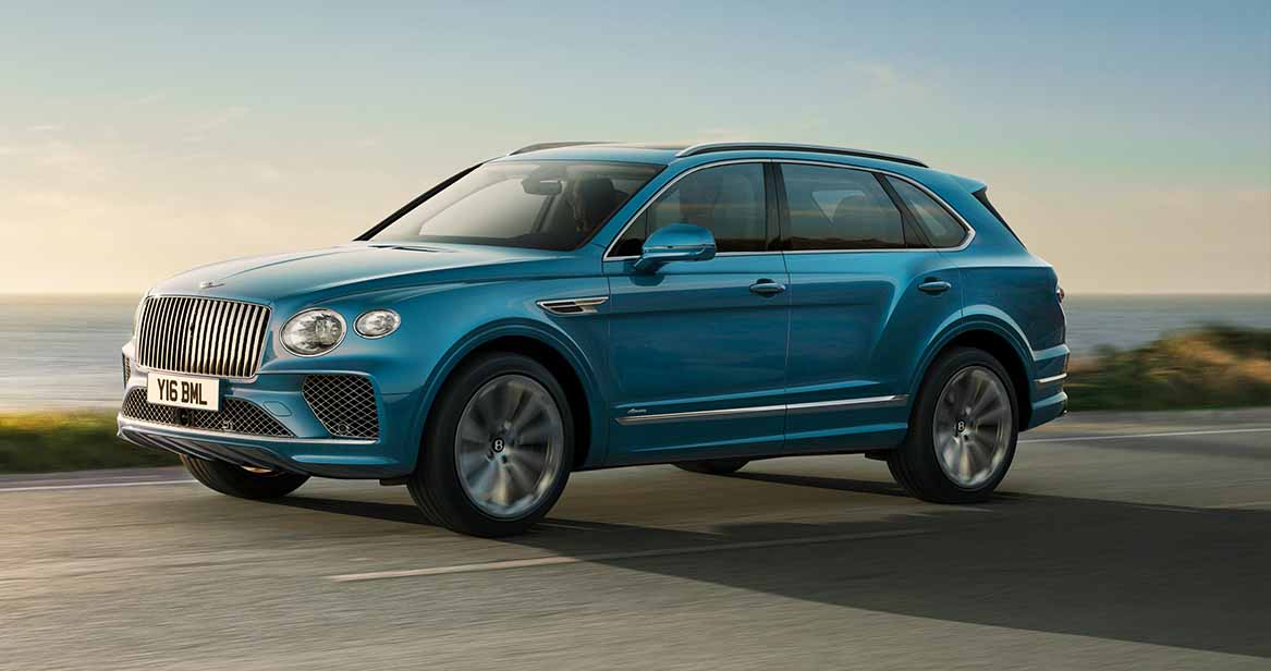 Side profile of a blue Bentley Bentayga parked under modern city lights at night.