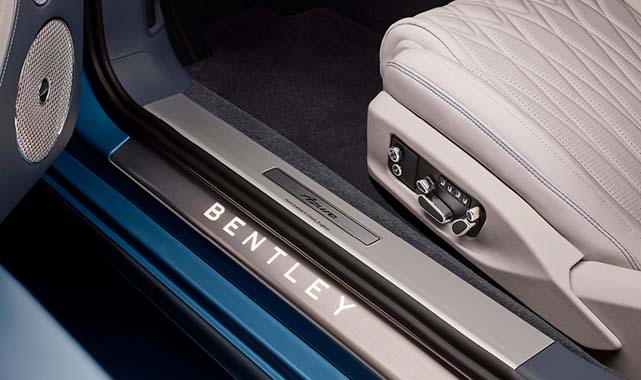 Close-up of the Bentley illuminated door sill plate and perforated leather seat with electronic adjustment controls, highlighting craftsmanship and comfort.