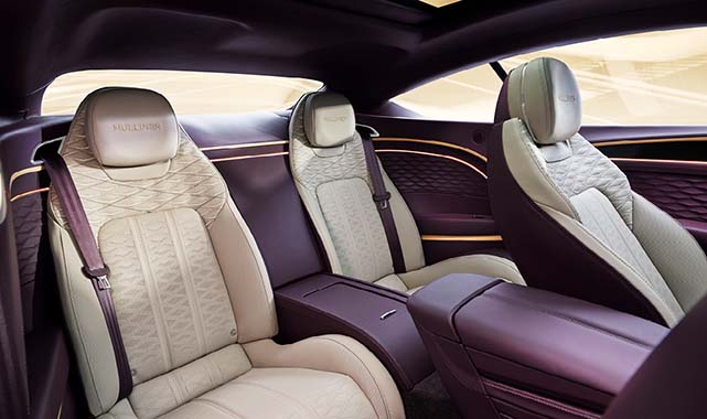 Rear cabin of the Bentley Continental GT Mulliner, featuring quilted leather seats, ambient lighting accents, and a sleek center console.