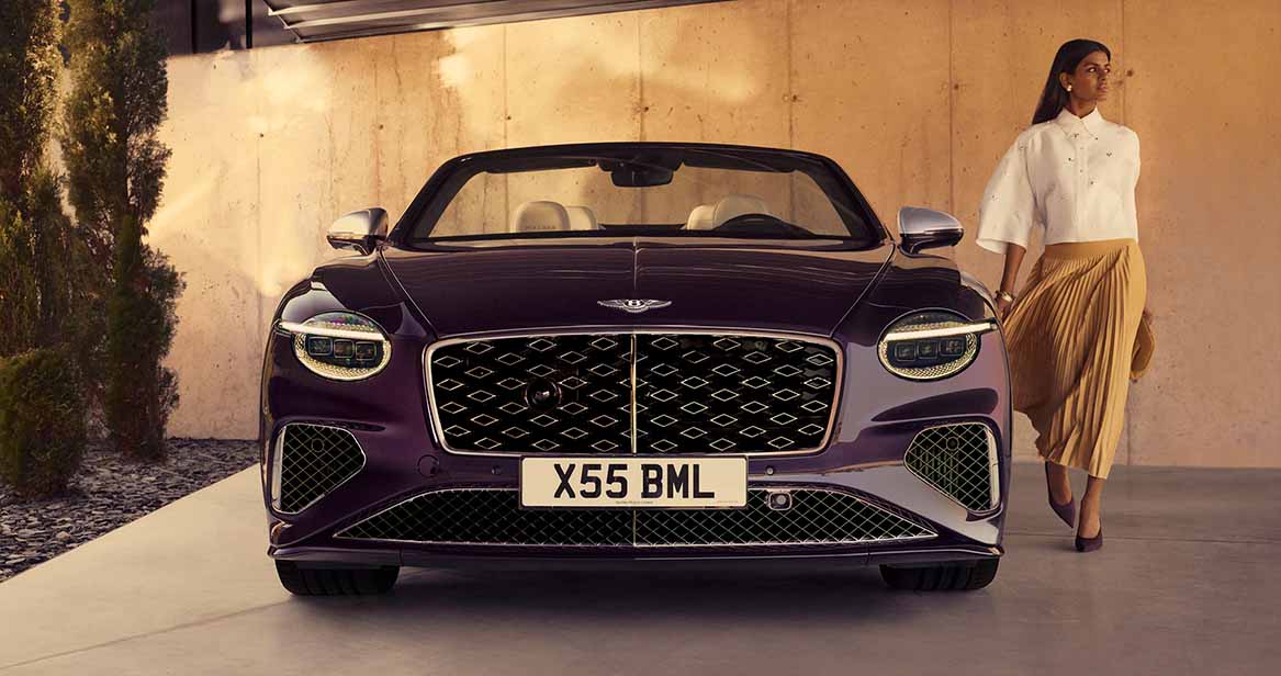 Front view of a deep purple Bentley Continental GTC convertible parked in a modern driveway.