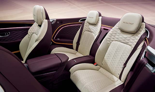 Rear seating of the Bentley Continental GTC Mulliner in a two-tone cream and plum leather design with quilted stitching and ambient lighting.