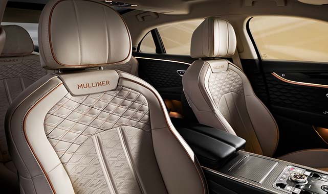 Front cabin view of the Bentley Flying Spur Mulliner, showcasing diamond-quilted leather seats embroidered with the “MULLINER” logo, separated by a luxurious center console.