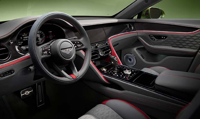 Bentley Flying Spur Speed with dark leather and red accent stitching, carbon fiber trim, and a digital cockpit setup emphasizing performance and craftsmanship.